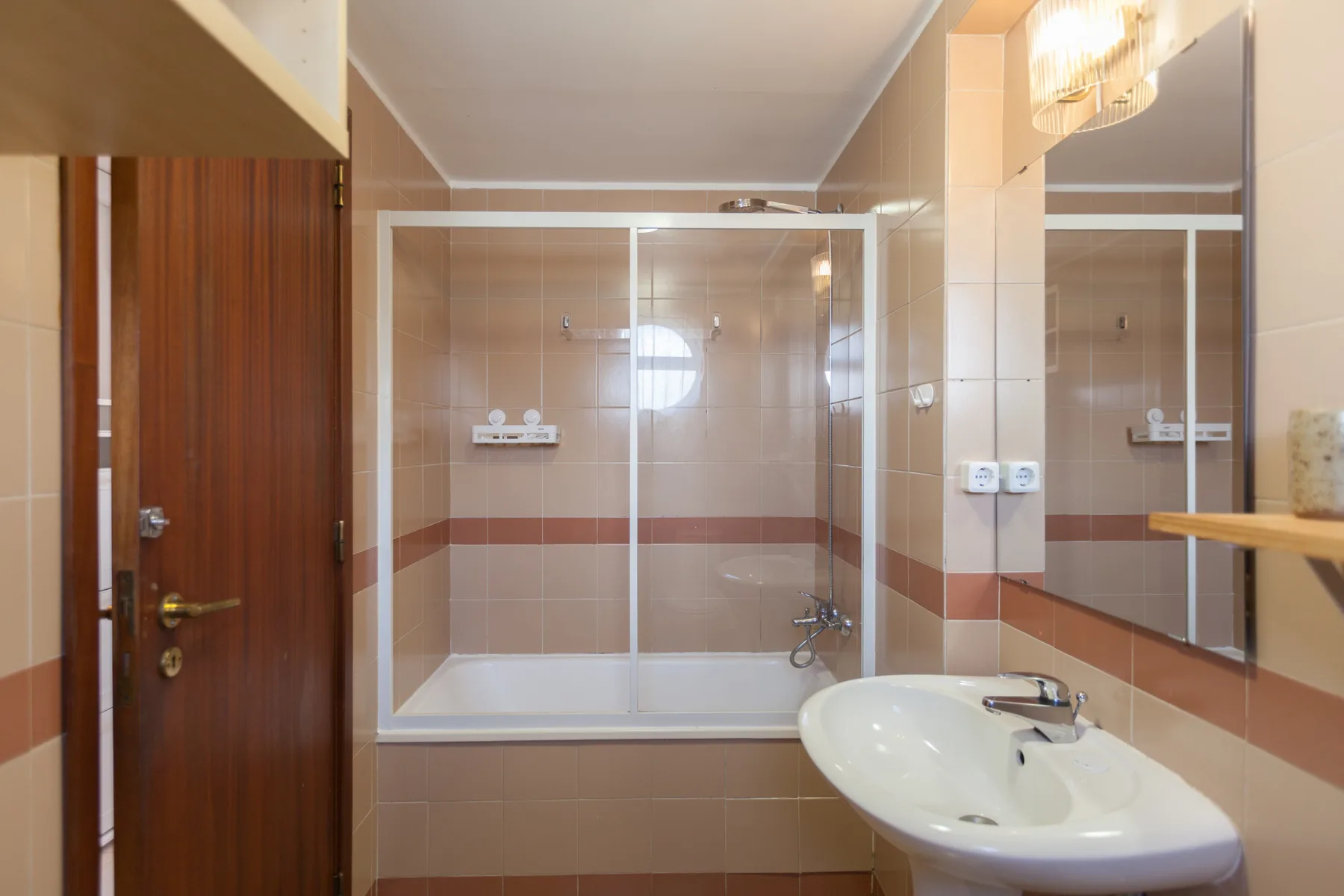 Un baño alicatado con una ducha de vidrio y un lavabo.