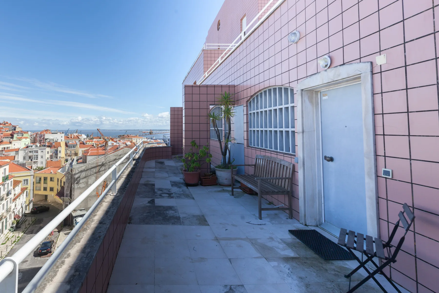 Una terraza en la azotea con asientos y plantas en macetas ofrece vistas a la ciudad.