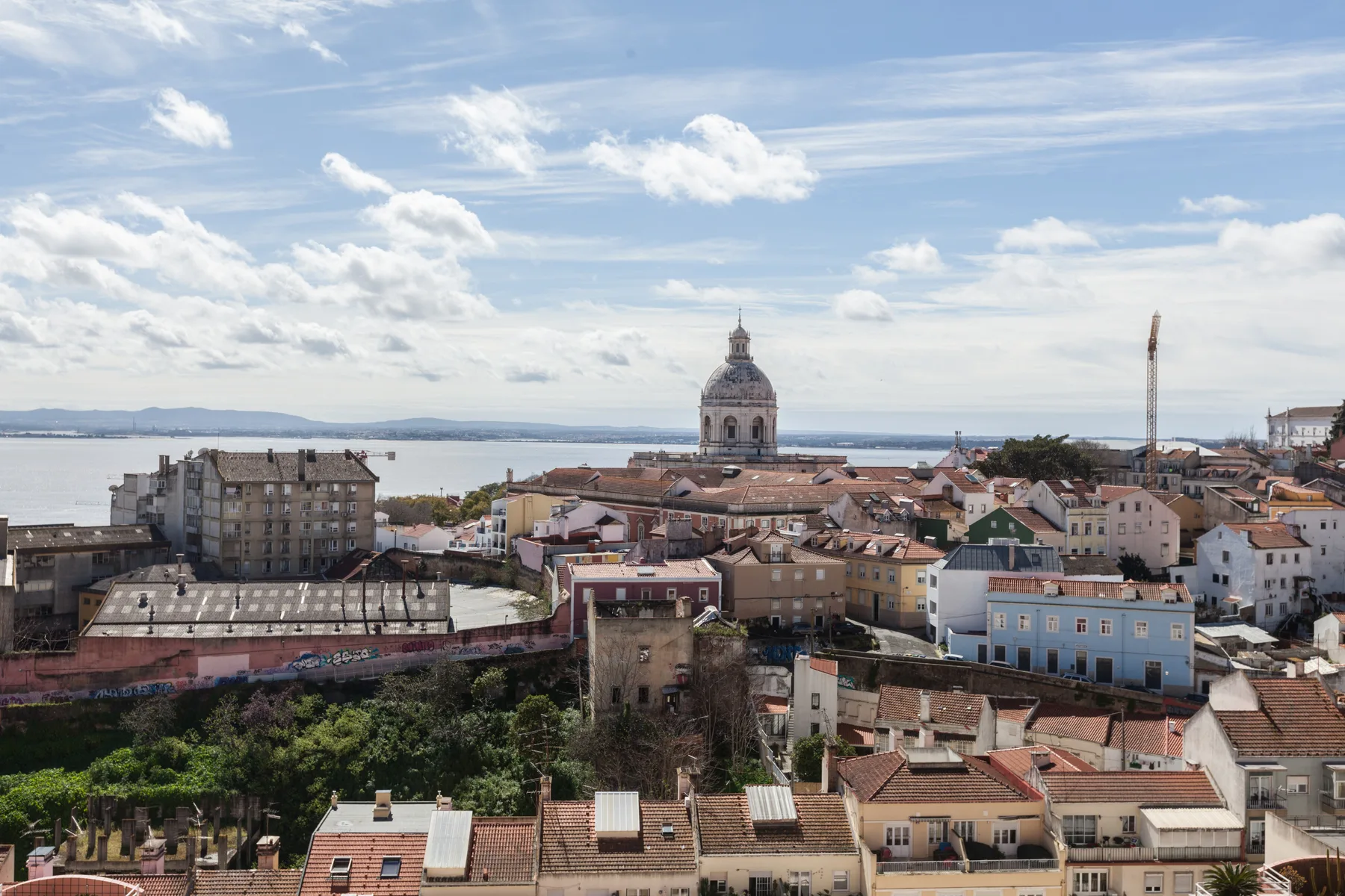 Paisaje urbano de Lisboa con tejados y edificios bajo un cielo parcialmente nublado.