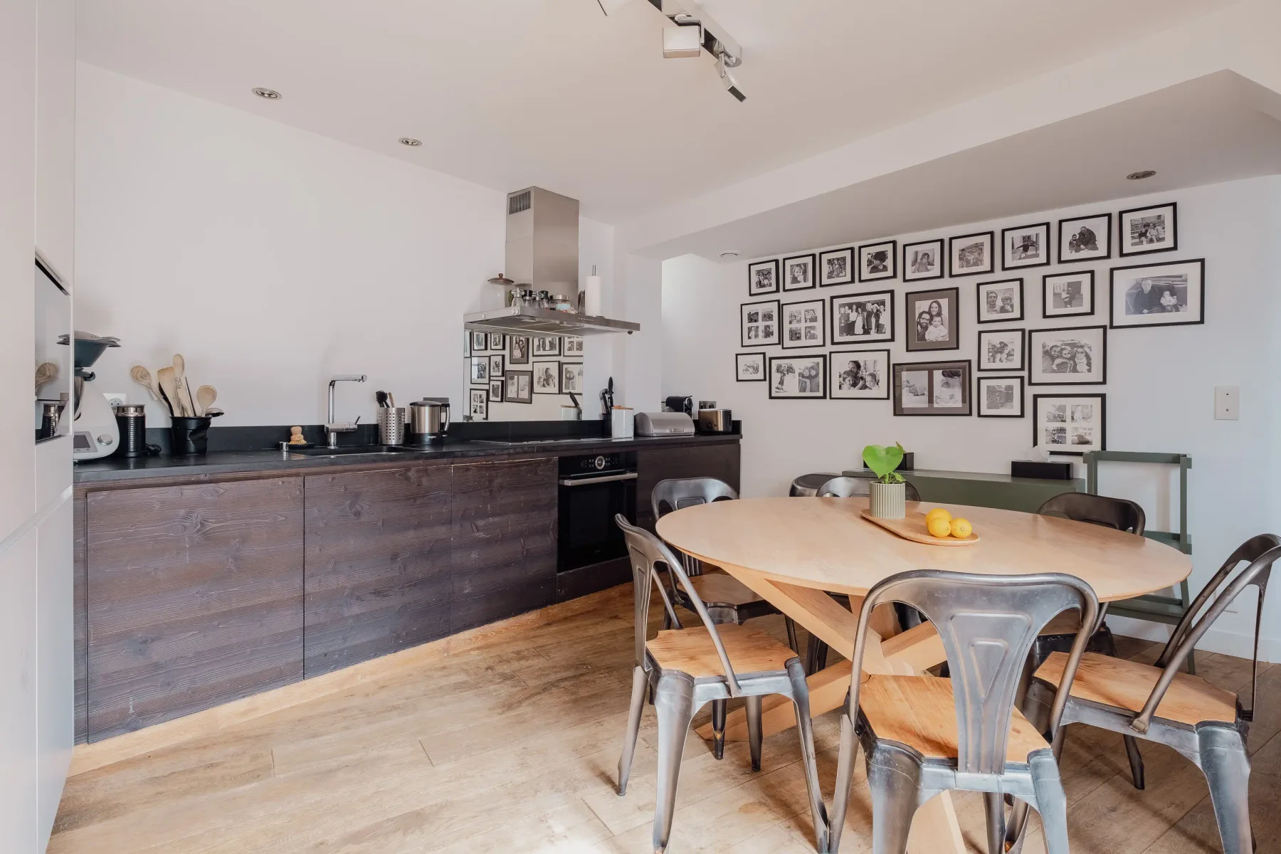 A kitchen and dining area with a table and framed pictures on the wall.