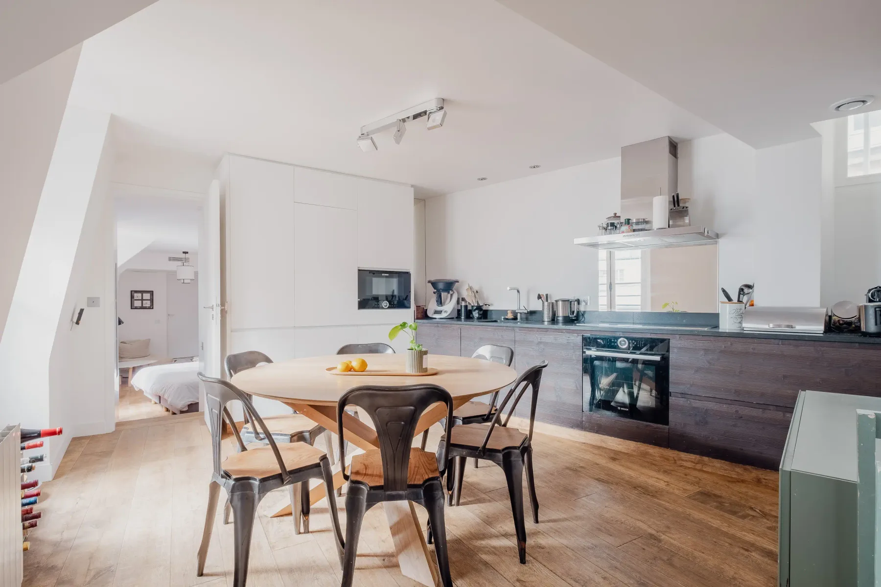 A bright kitchen and dining area with a wooden table and modern cabinets.