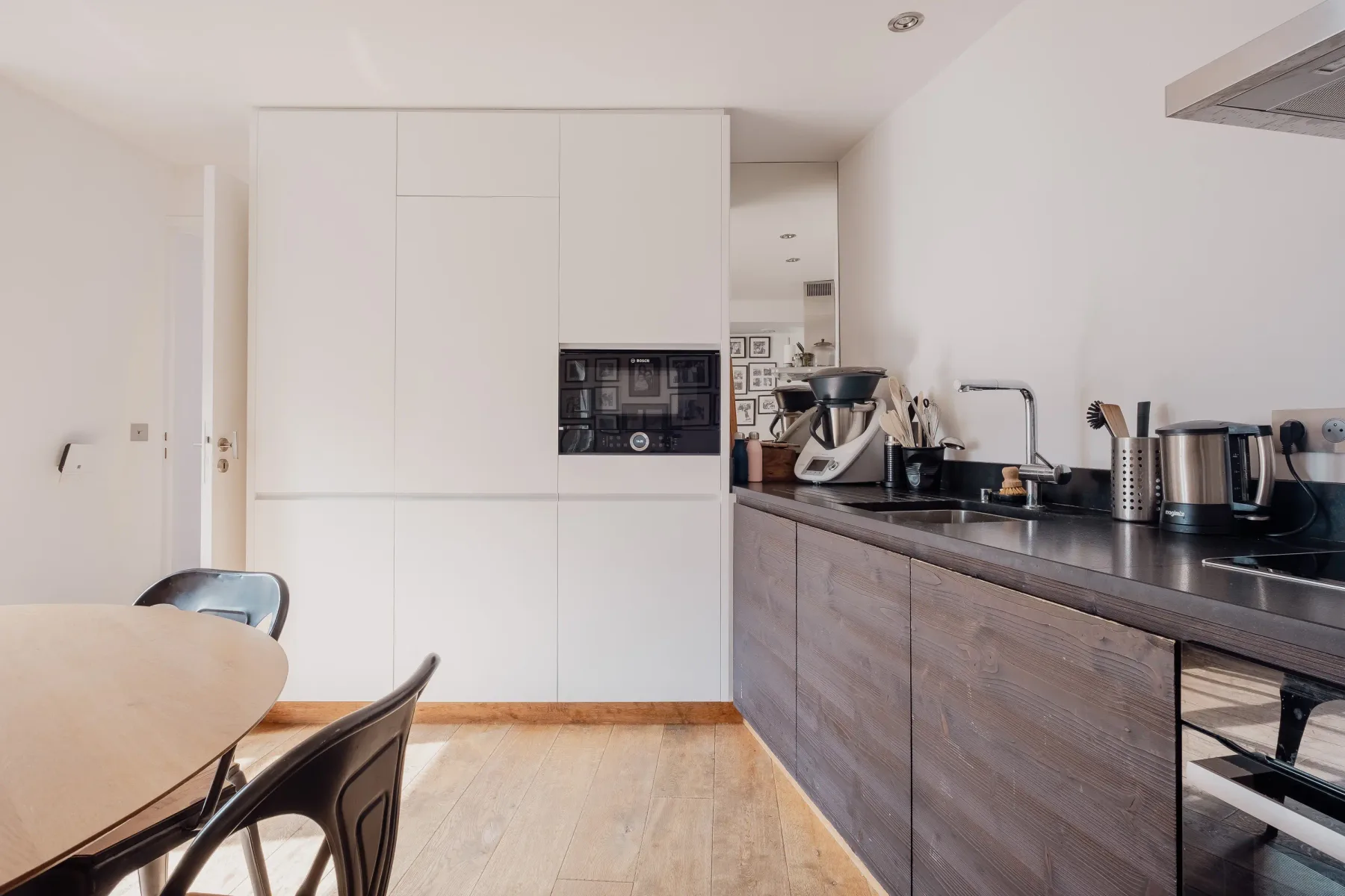 A modern kitchen with built-in appliances and a dining table.