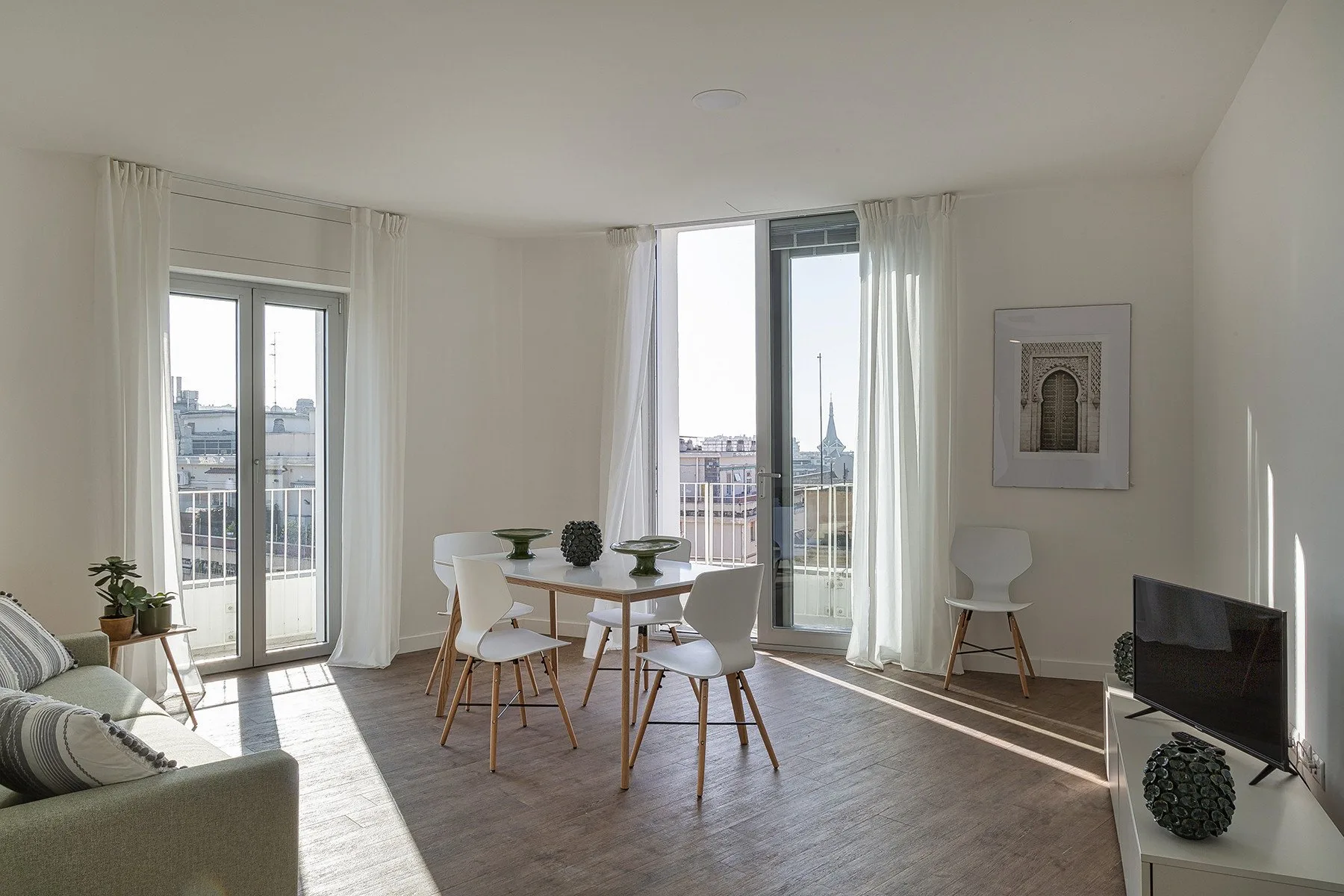 Una luminosa sala de estar y comedor con mesa, asientos y ventanas altas.