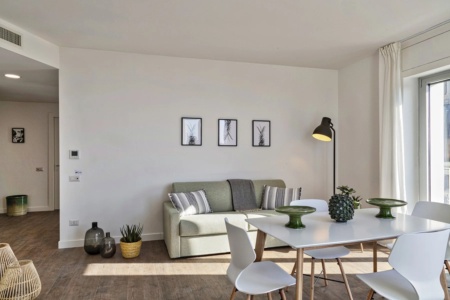 Una luminosa sala de estar y comedor con asientos, una mesa y grandes ventanas.