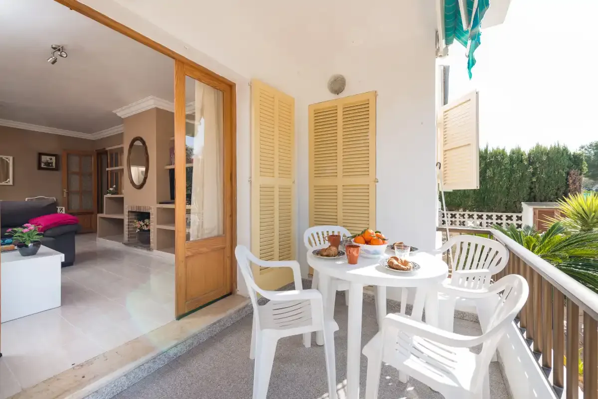 A furnished patio with white seating and a view into the living room.