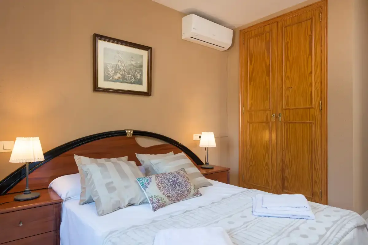 A bedroom with a neatly made bed and wooden wardrobe.