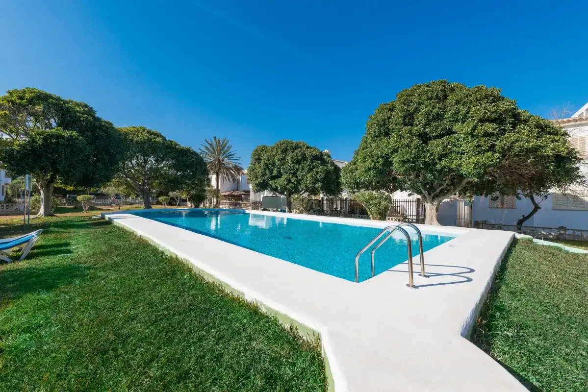 An outdoor swimming pool sits among green lawns and trees.