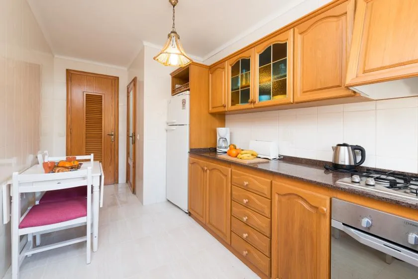 A kitchen with wooden cabinets, a countertop, and a small dining table.