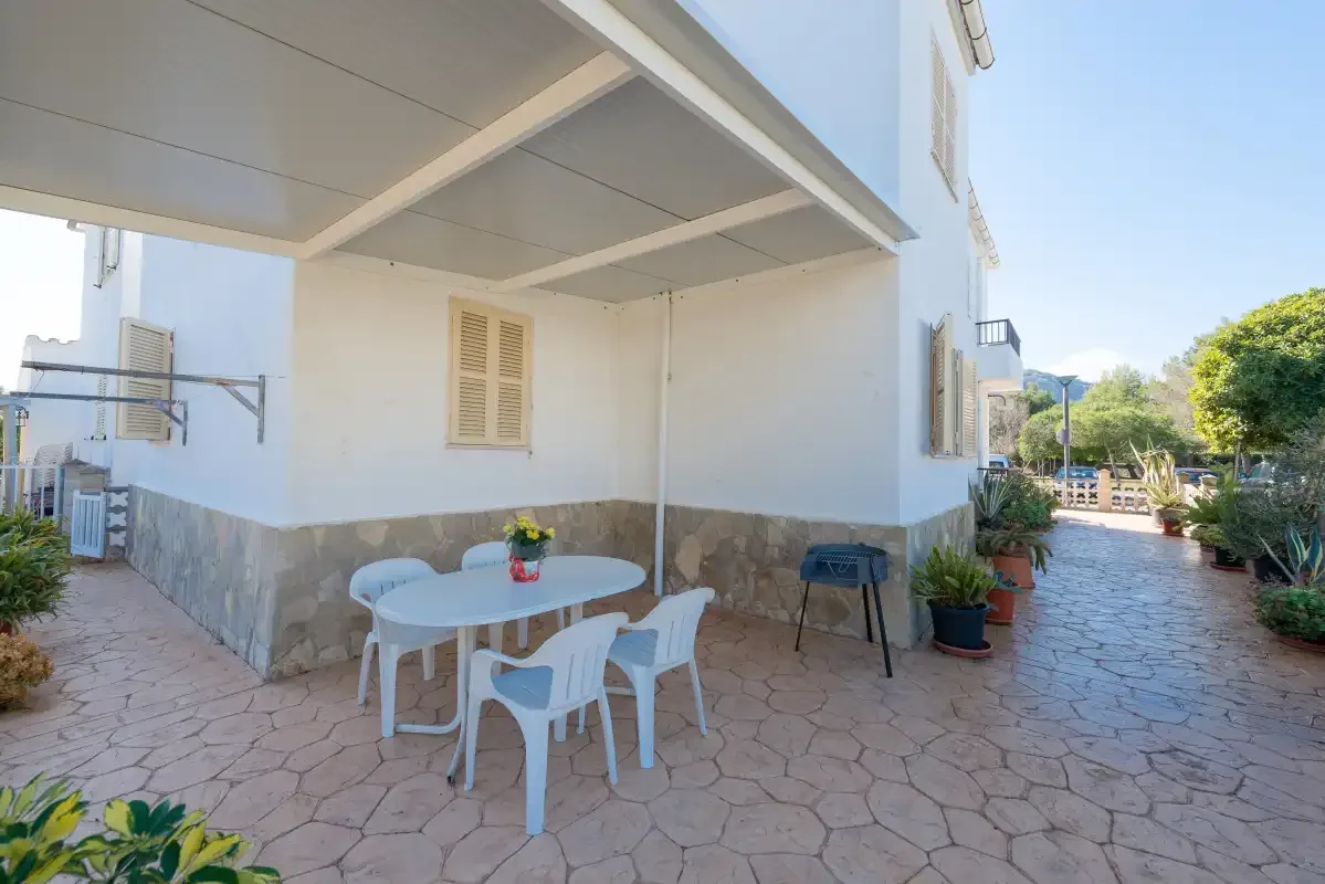 A covered outdoor dining area with a table and seating beside the building.