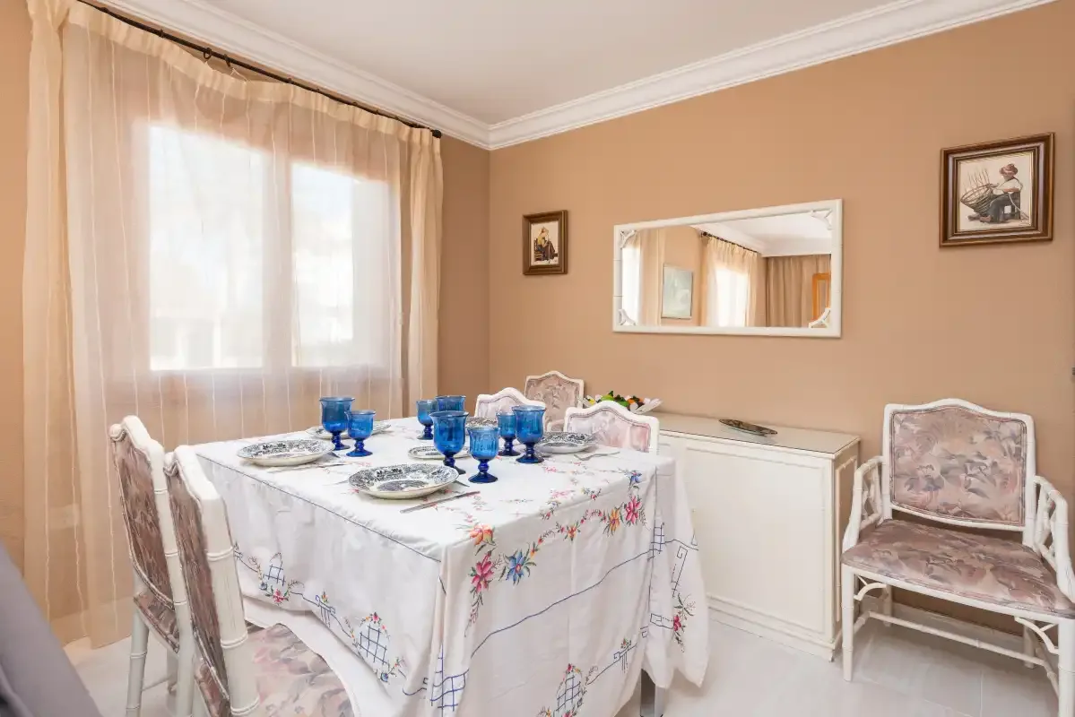 A dining room with a set table beside a window.
