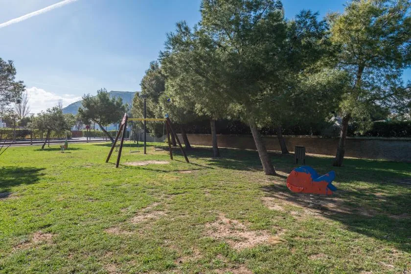 A grassy outdoor play area with swings and trees.