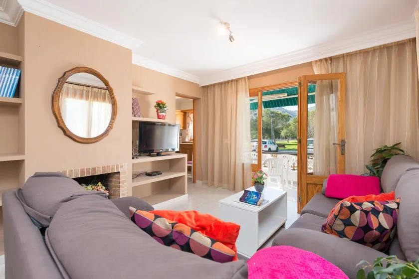 A living room with seating, a television, and glass doors opening onto a balcony.