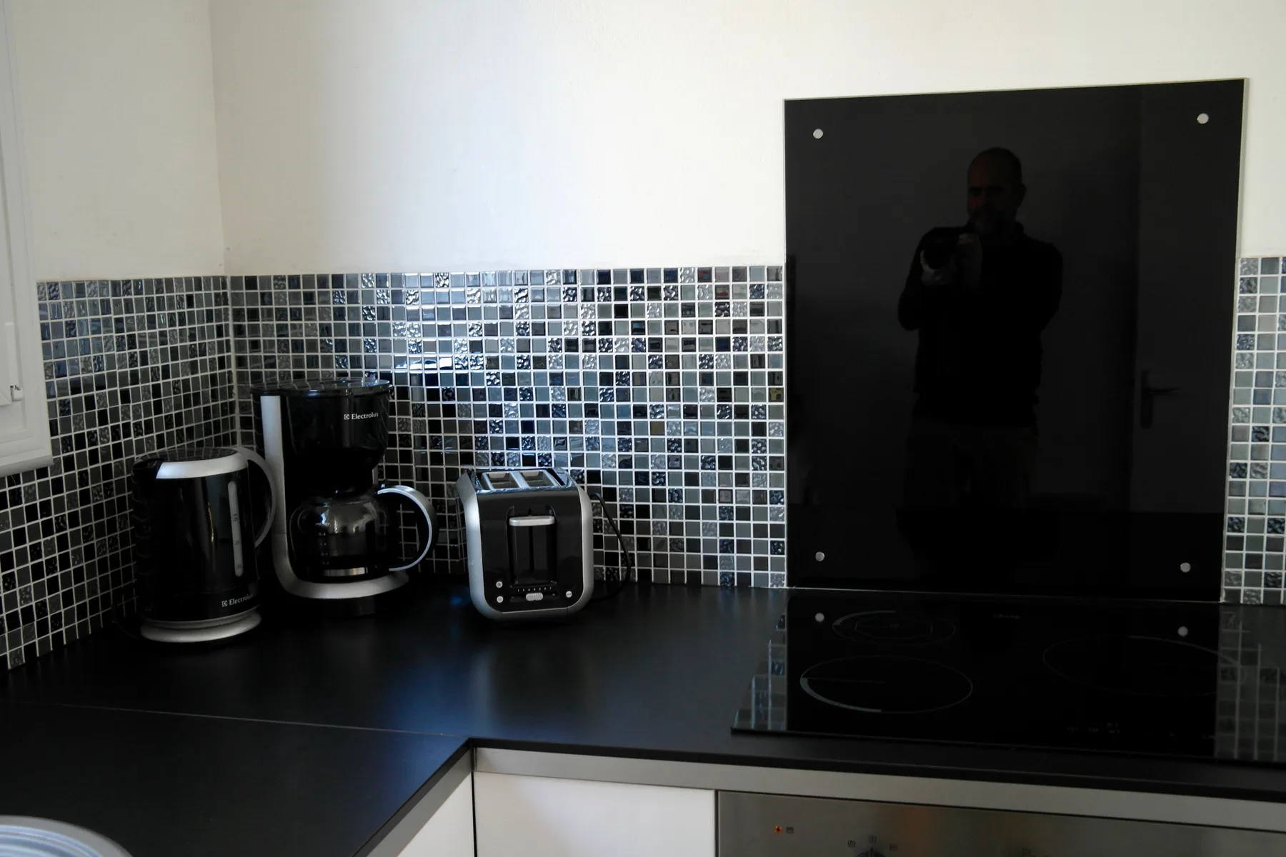 A kitchen counter with small appliances beside a black cooktop.