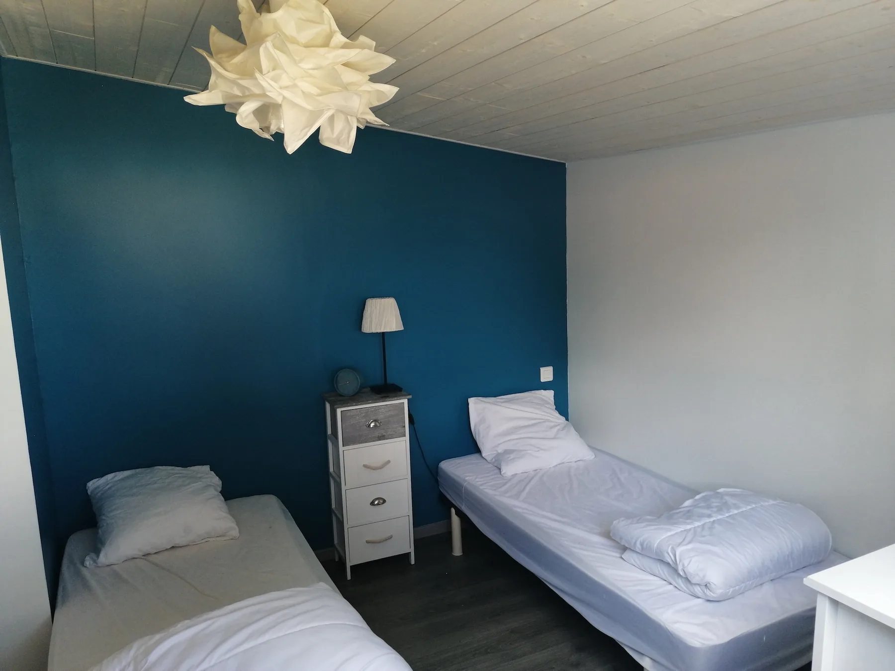 A bedroom with two single beds and a small bedside cabinet.