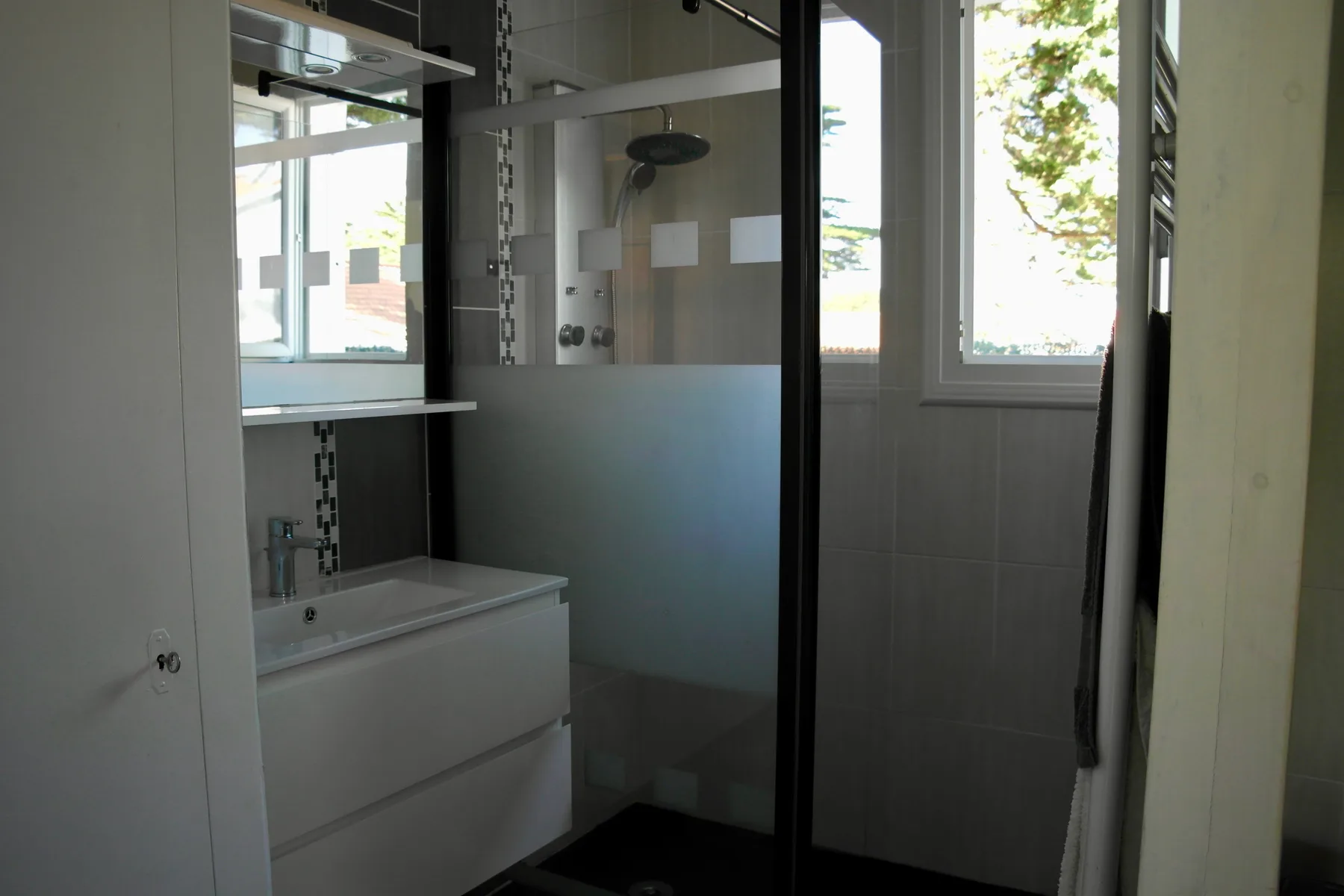 A bathroom with a sink vanity and a glass shower.