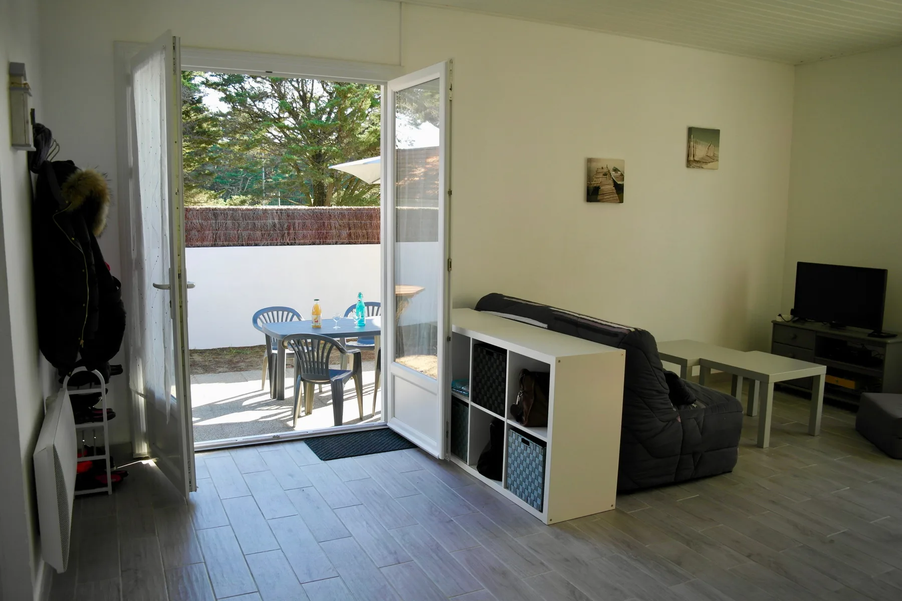 A living room opens onto a patio with outdoor seating and a table.