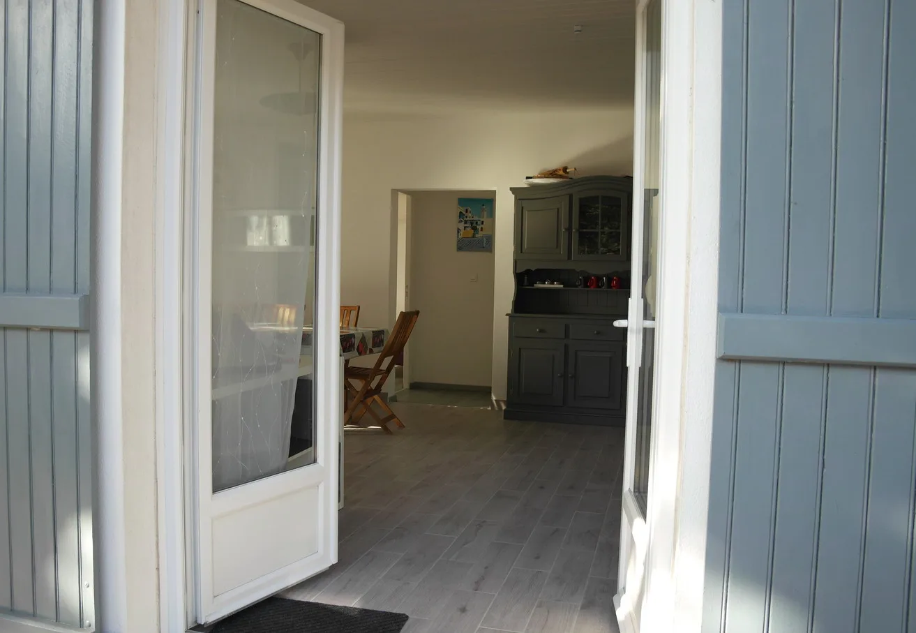 An open doorway looks into a dining area with a table and chairs.