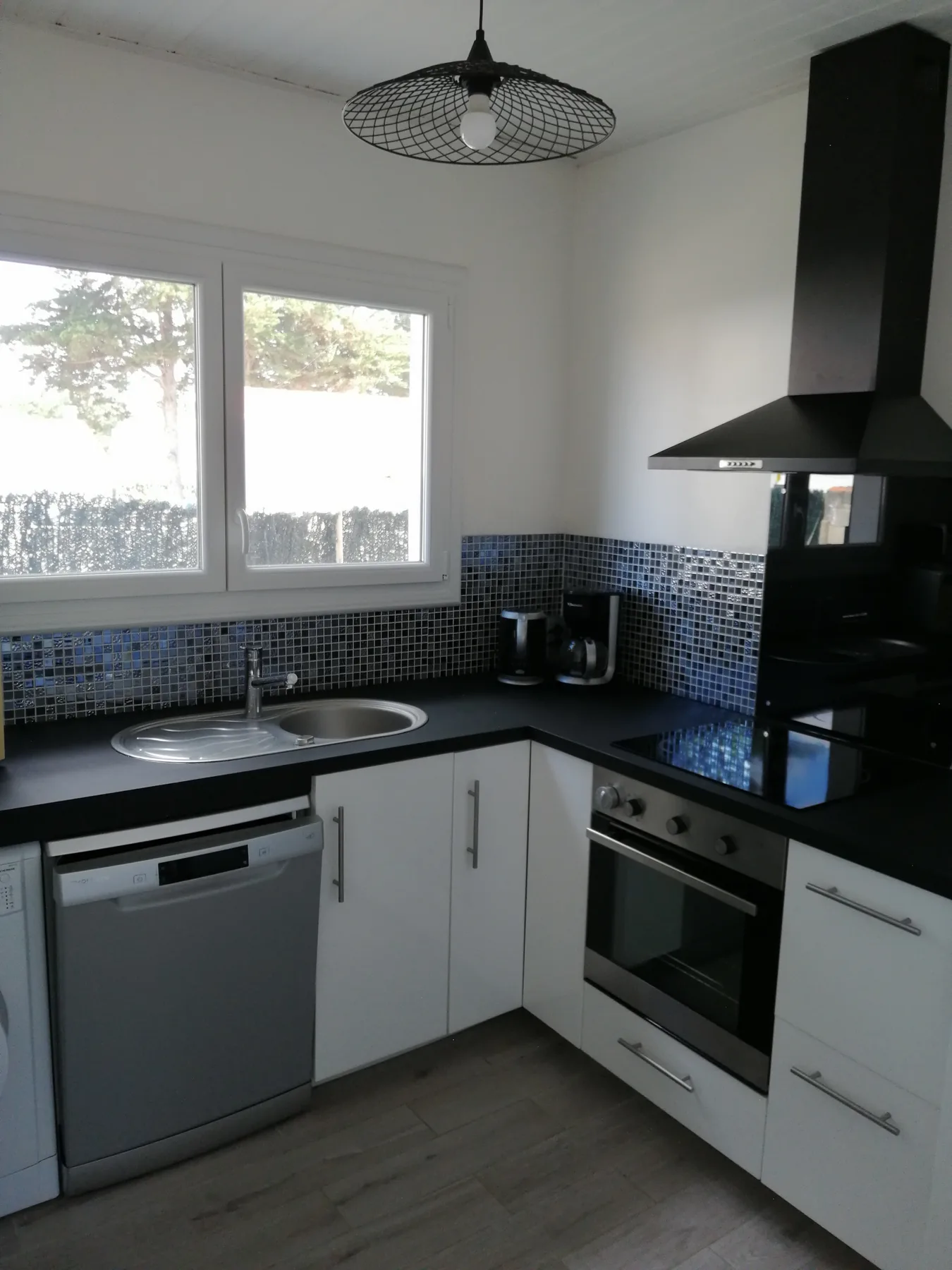 A kitchen with an L-shaped counter, sink, and built-in oven.