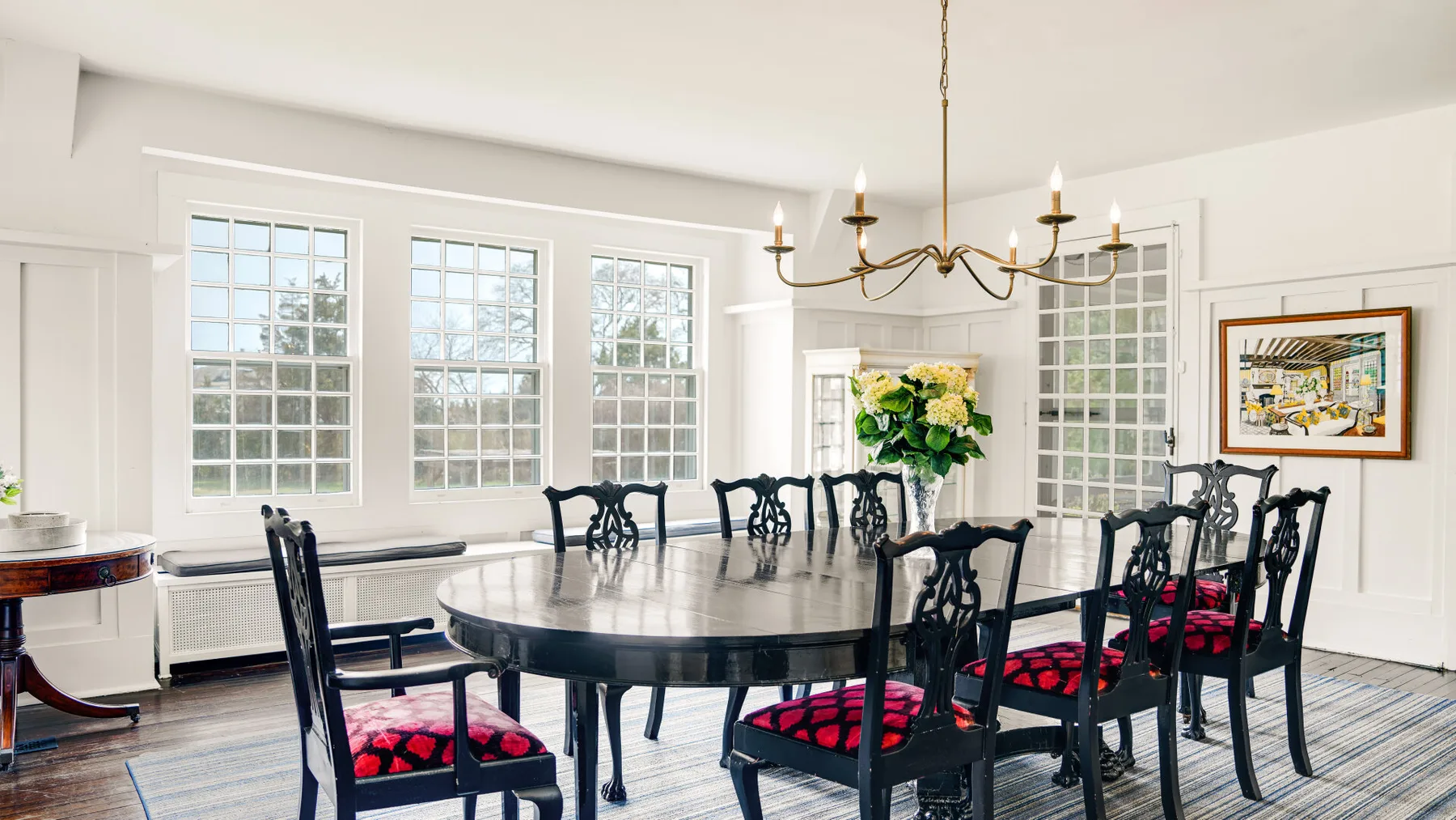 Un comedor luminoso con una mesa larga, sillas oscuras y ventanas grandes.