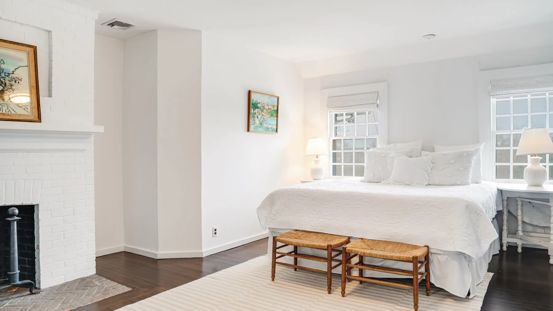 Un dormitorio luminoso con una cama tendida y dos bancos de madera.