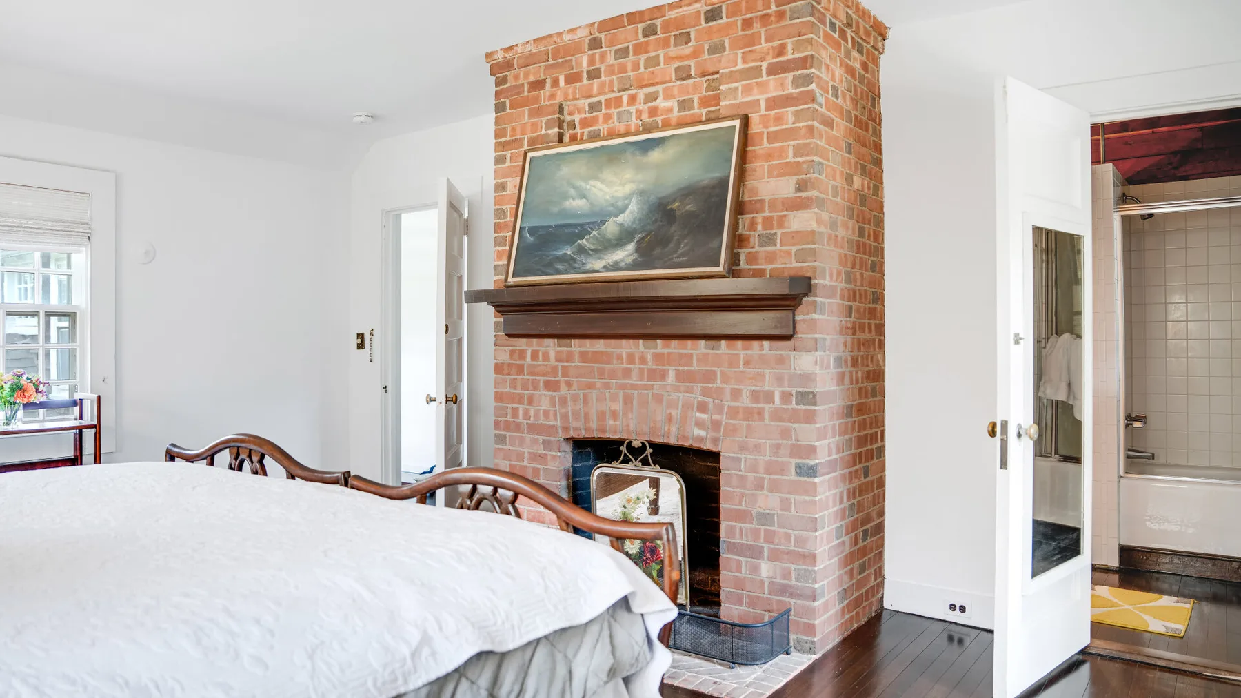 Un dormitorio con una chimenea de ladrillo y una cama en primer plano.