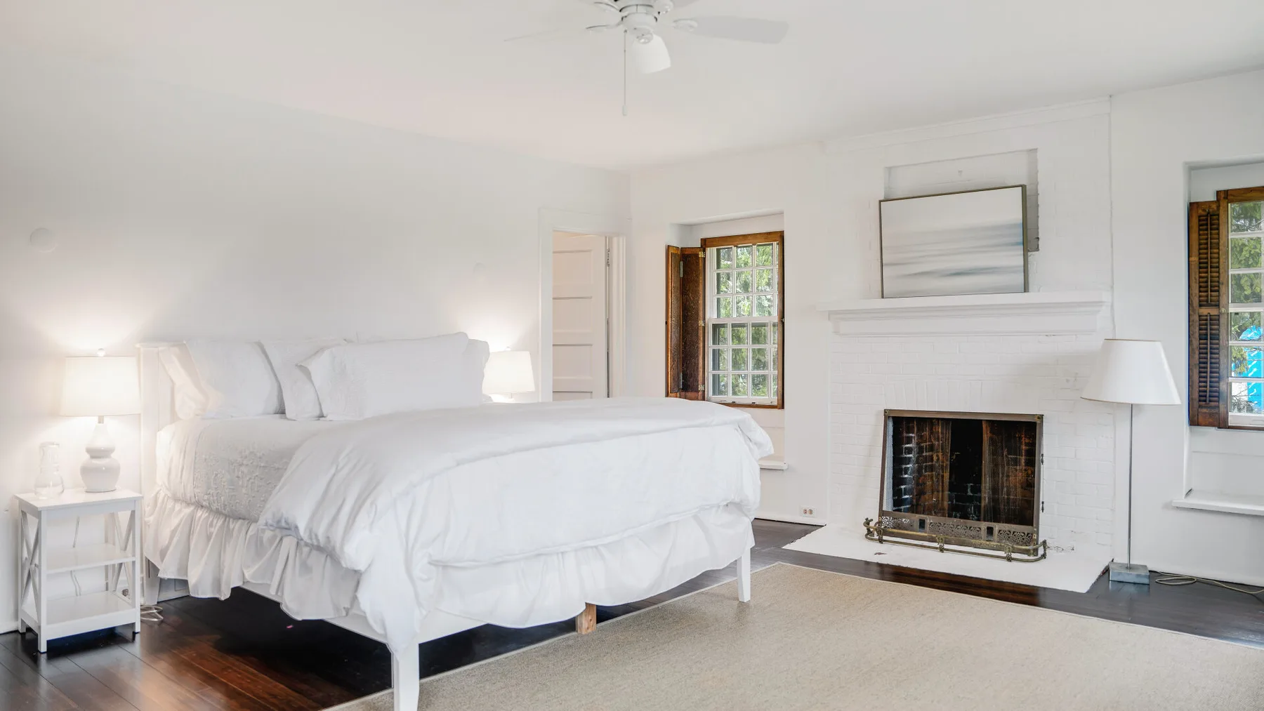 Un dormitorio luminoso con una cama blanca y una chimenea.
