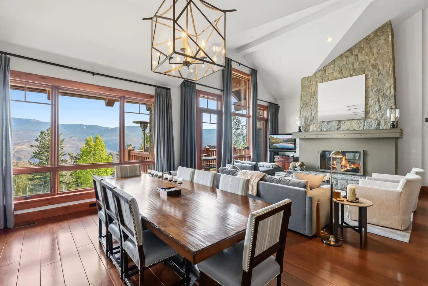 A dining area opens into a living room with a fireplace and large windows.