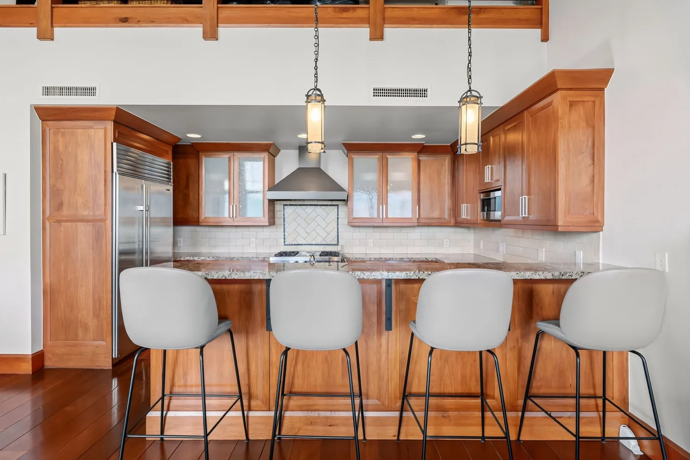 A kitchen with a long counter, wooden cabinets, and bar seating.