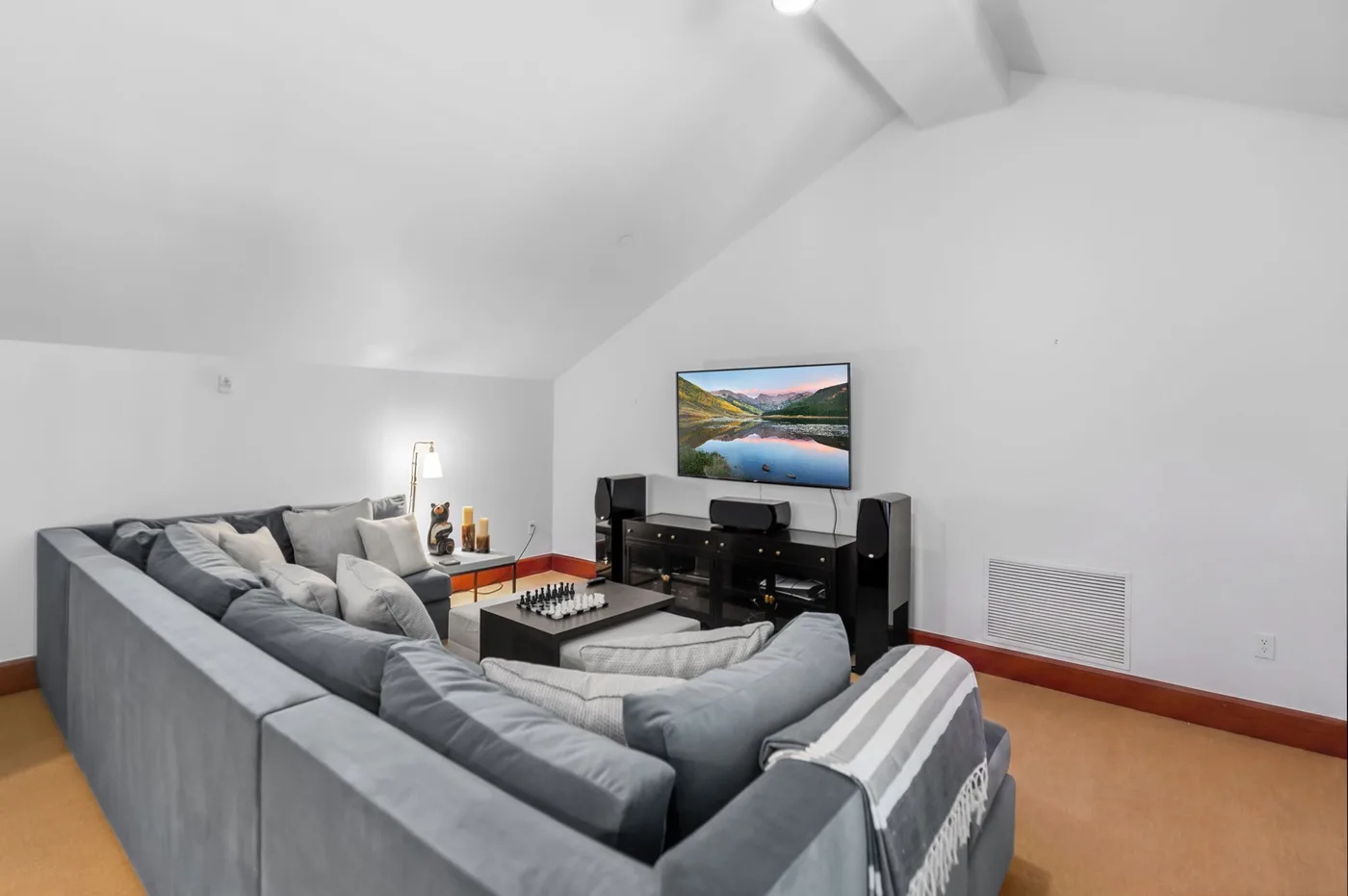 A living room with gray seating facing a television and media console.