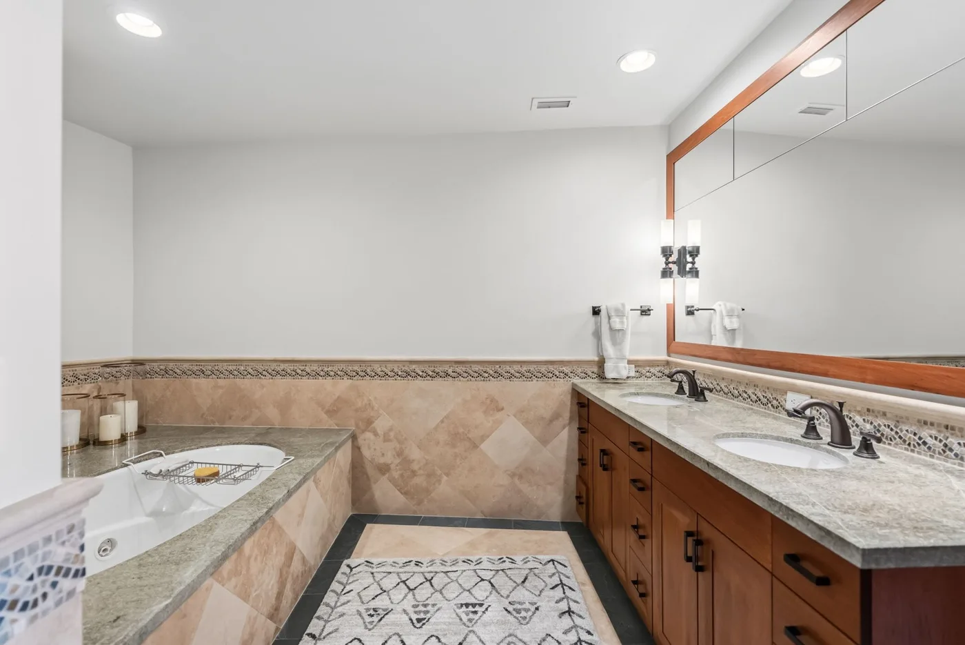 A bright bathroom with a bathtub, a long vanity, and a large mirror.