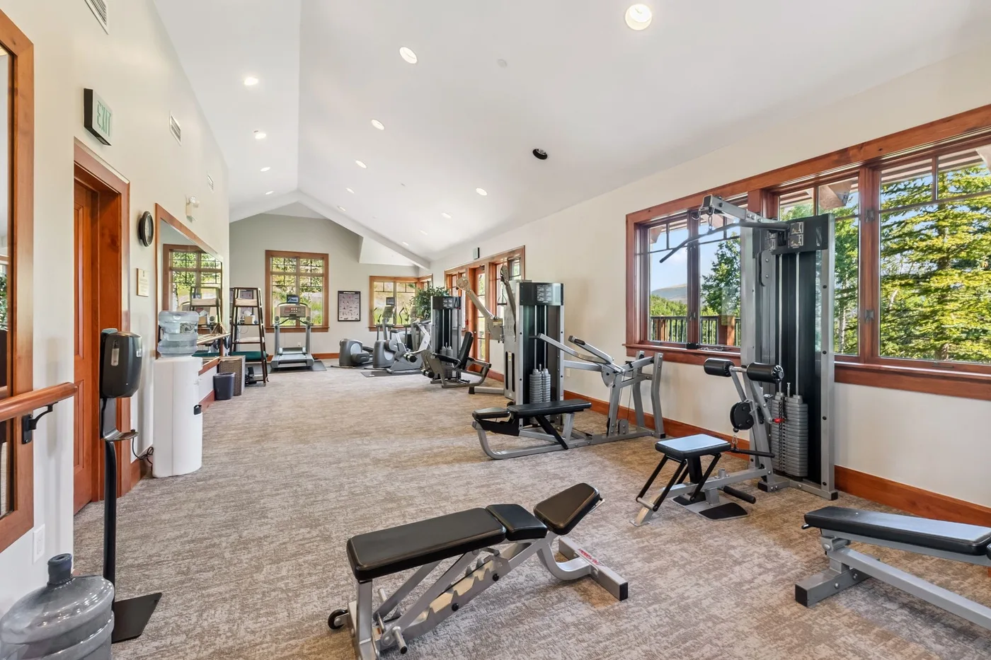 A fitness room with exercise machines, weights, and large windows.