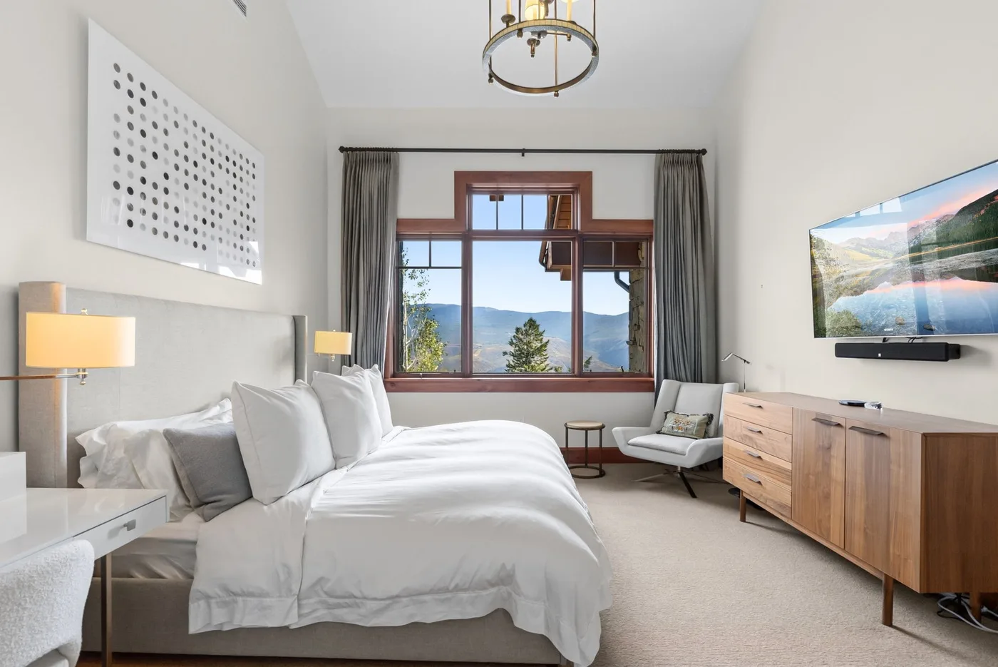 A bright bedroom with a large bed, a window, and a seating area.