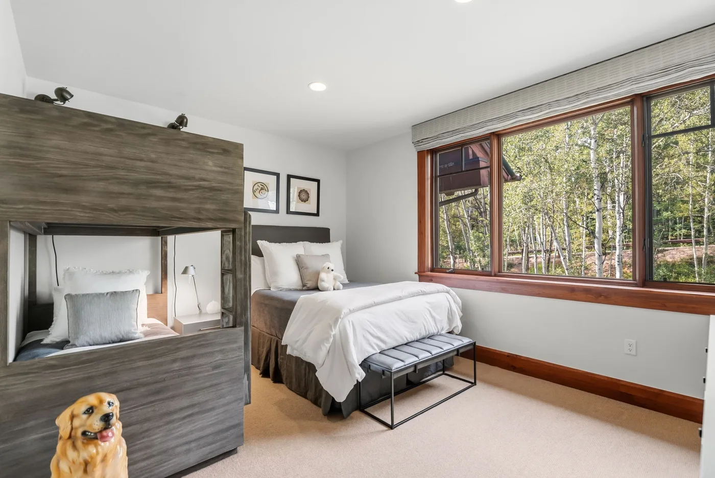 A bright bedroom with a neatly made bed beside a large window.
