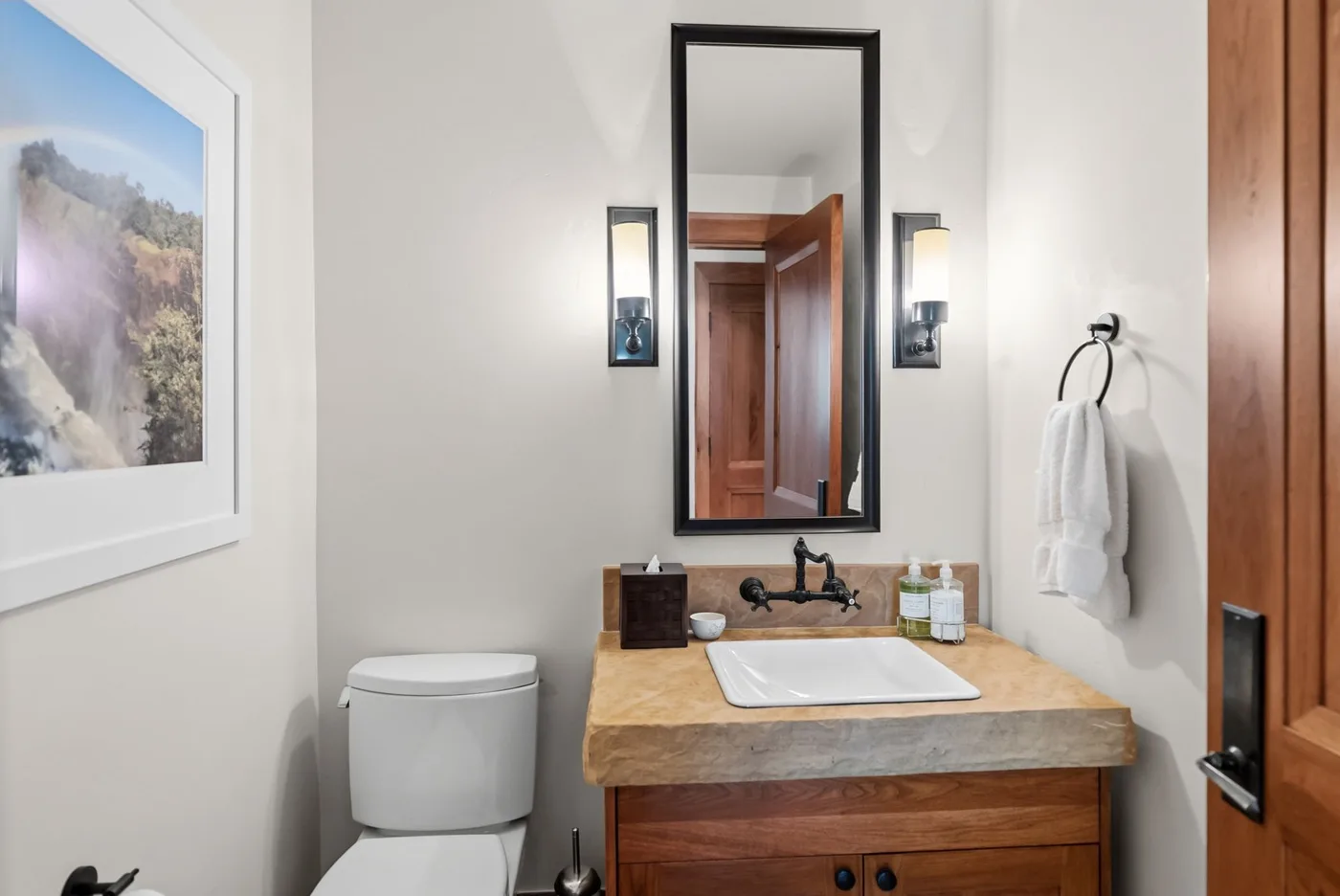 A bathroom vanity with a sink sits beneath a mirror between wall lights.