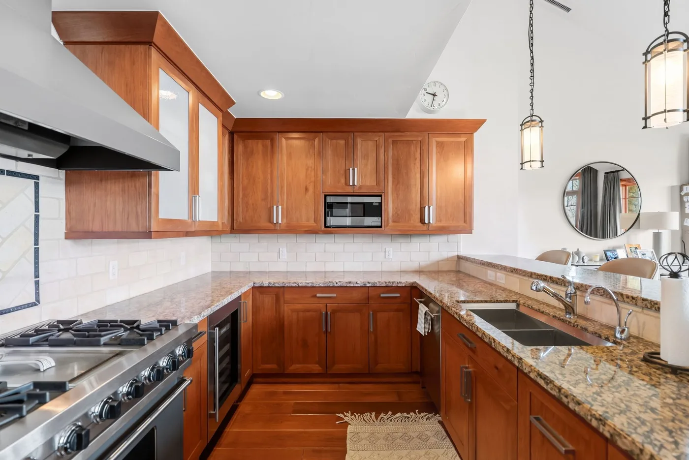 A kitchen with wooden cabinets, stone countertops, and stainless steel appliances.