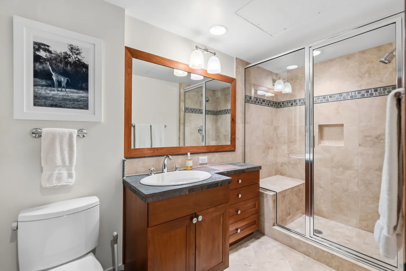 A bathroom with a wooden vanity, sink, and glass-enclosed shower.