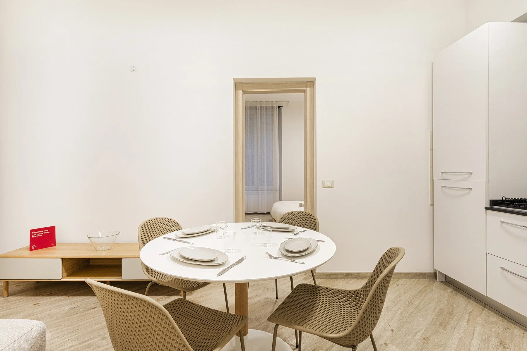 Un comedor luminoso con una mesa redonda y asientos tejidos.