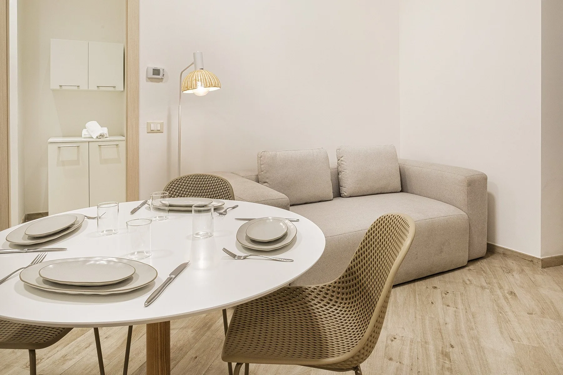 A dining area with a set table and beige seating.
