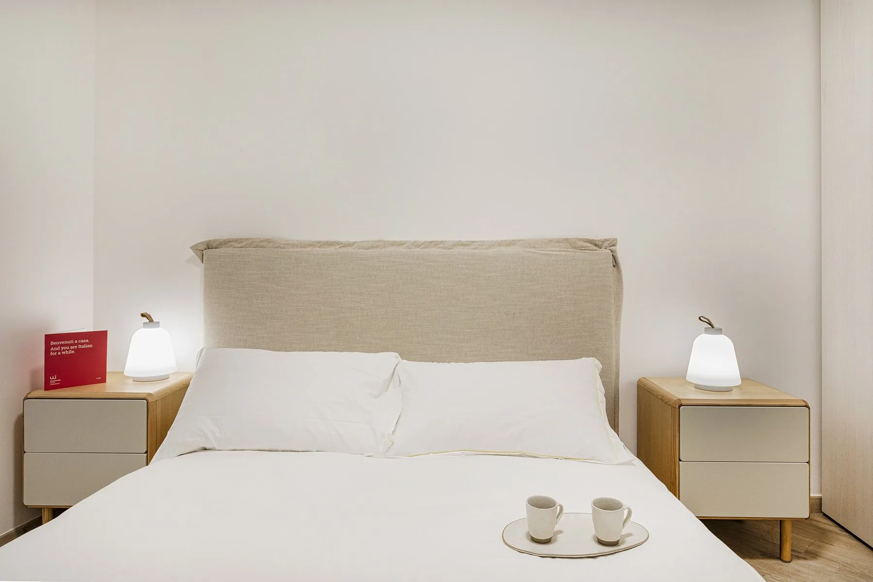 Un dormitorio con una cama bien arreglada y mesitas de noche a juego.
