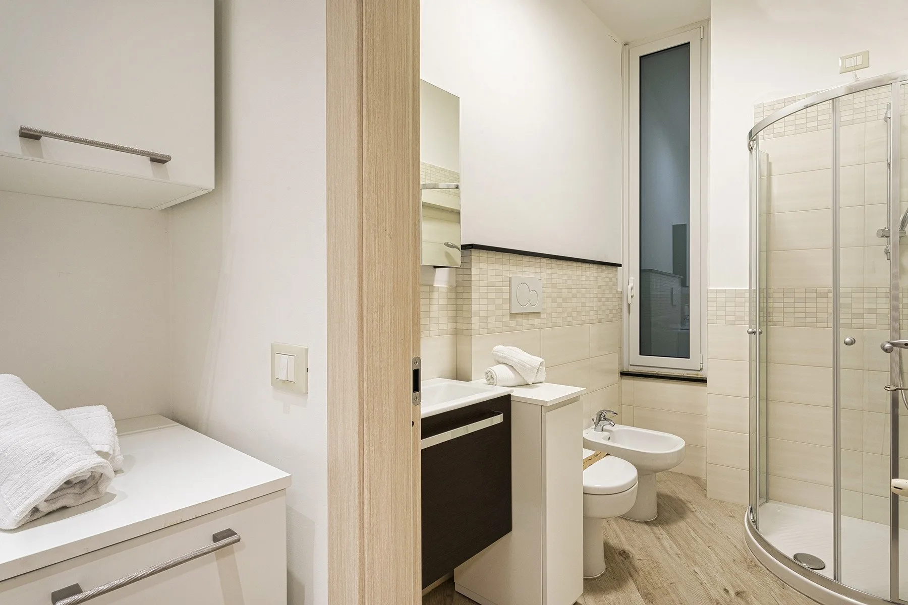 Un baño con lavabo, inodoro y ducha con mampara de vidrio.