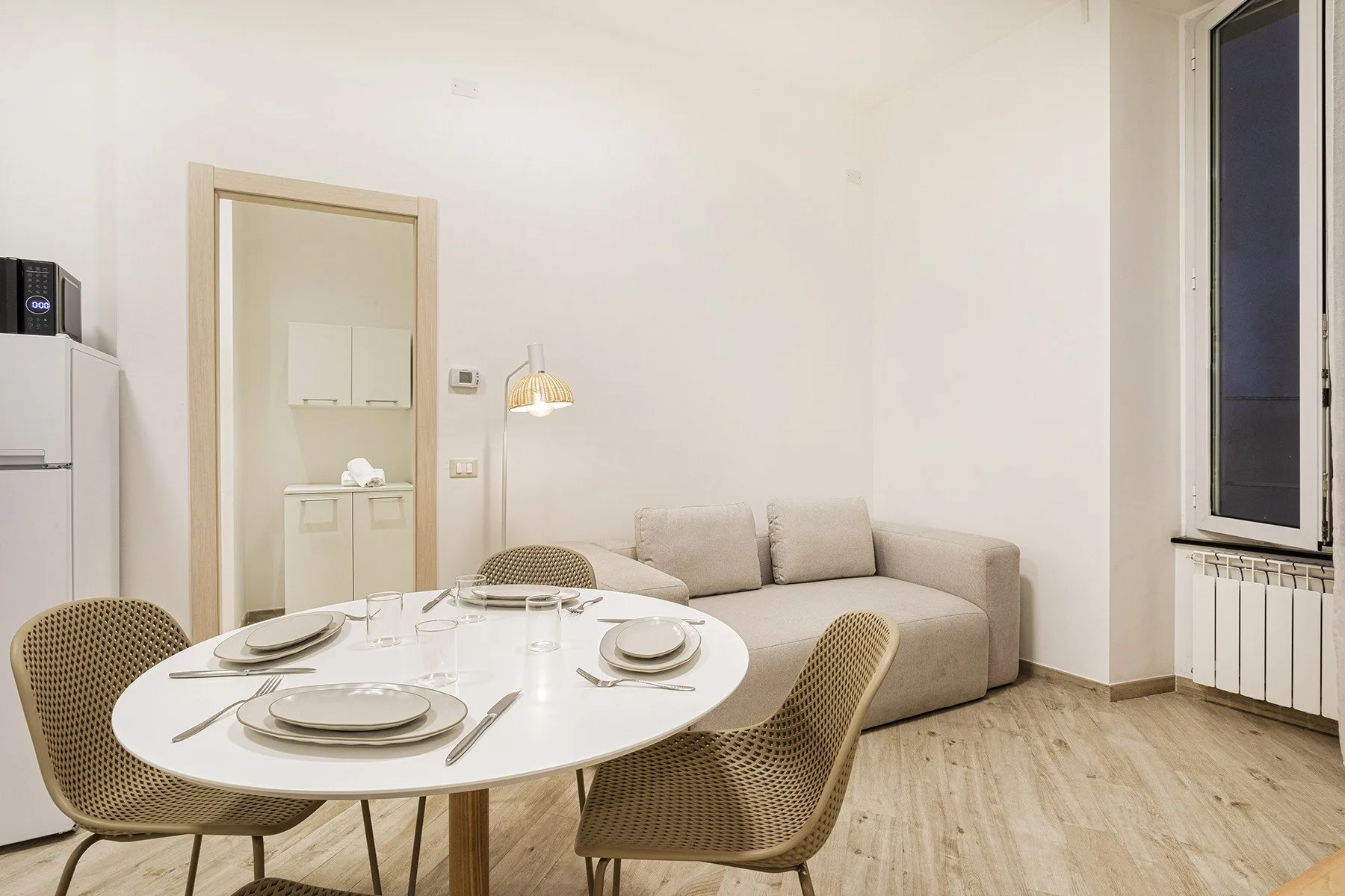 Una luminosa zona de comedor con la mesa puesta junto a un sofá beige.
