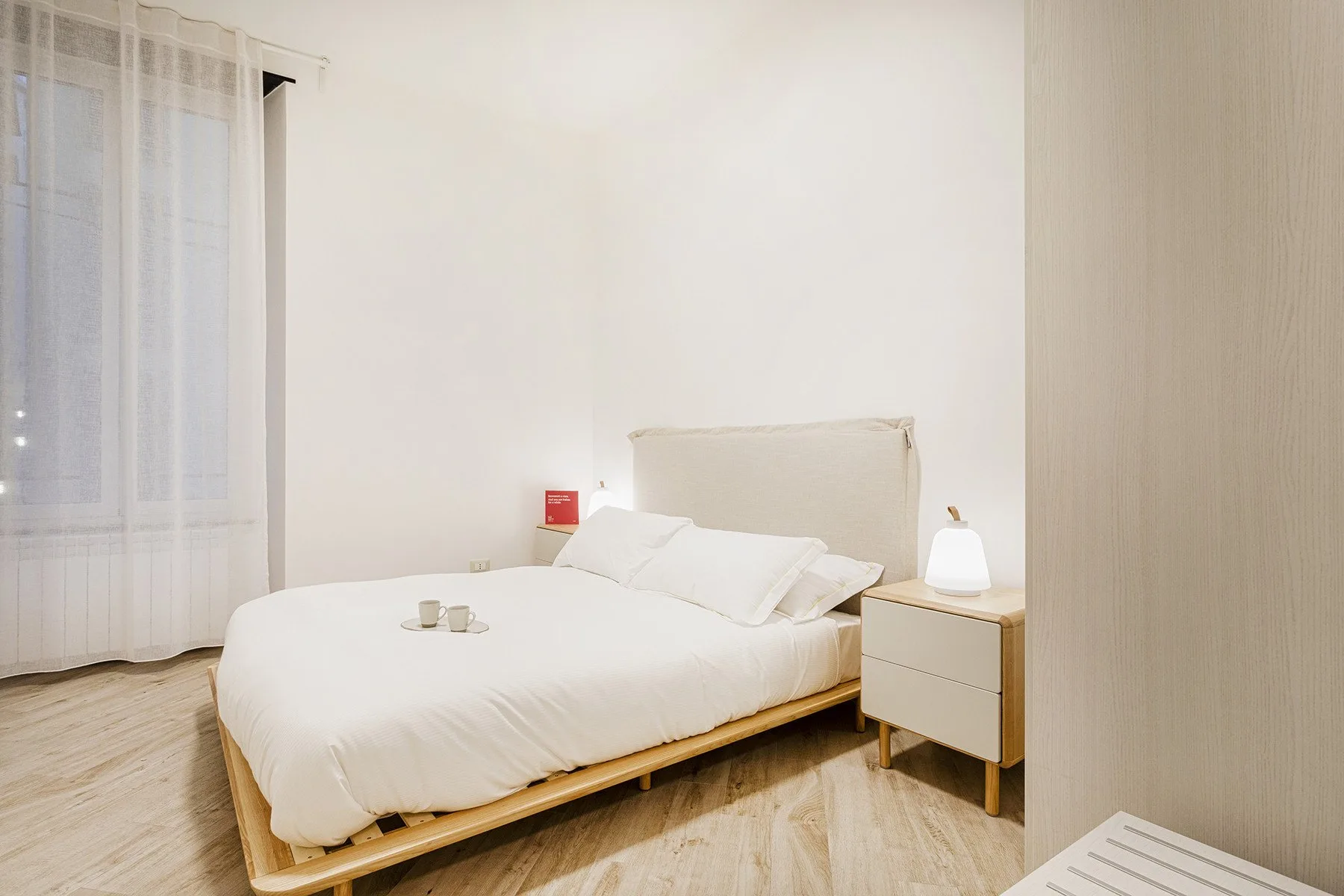 Un dormitorio luminoso con una cama junto a una ventana con cortinas.