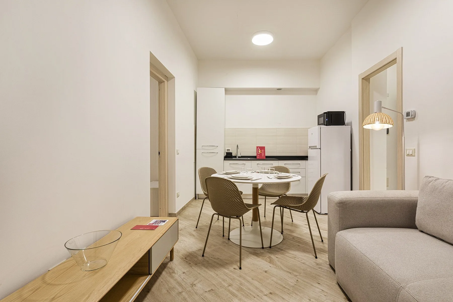 Una luminosa sala de estar y comedor con mesa, asientos y una pequeña cocina.