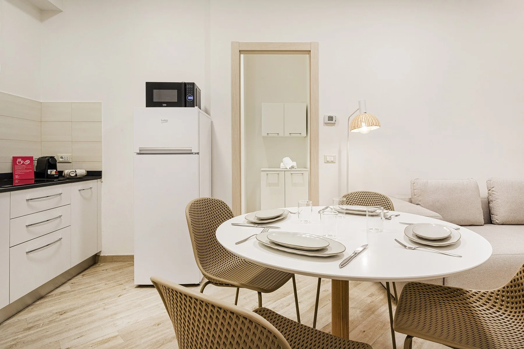 A dining area with a round table and a compact kitchen beside it.