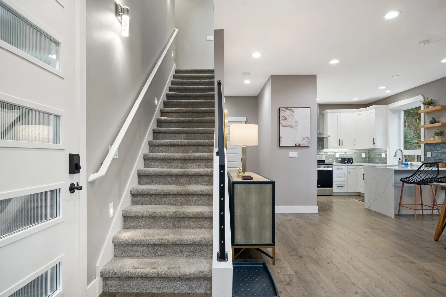 Interior de planta abierta con una escalera, una mesa pequeña y una cocina.
