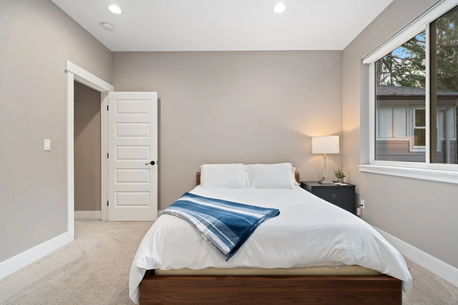 Un dormitorio con una cama bien tendida y una ventana grande.