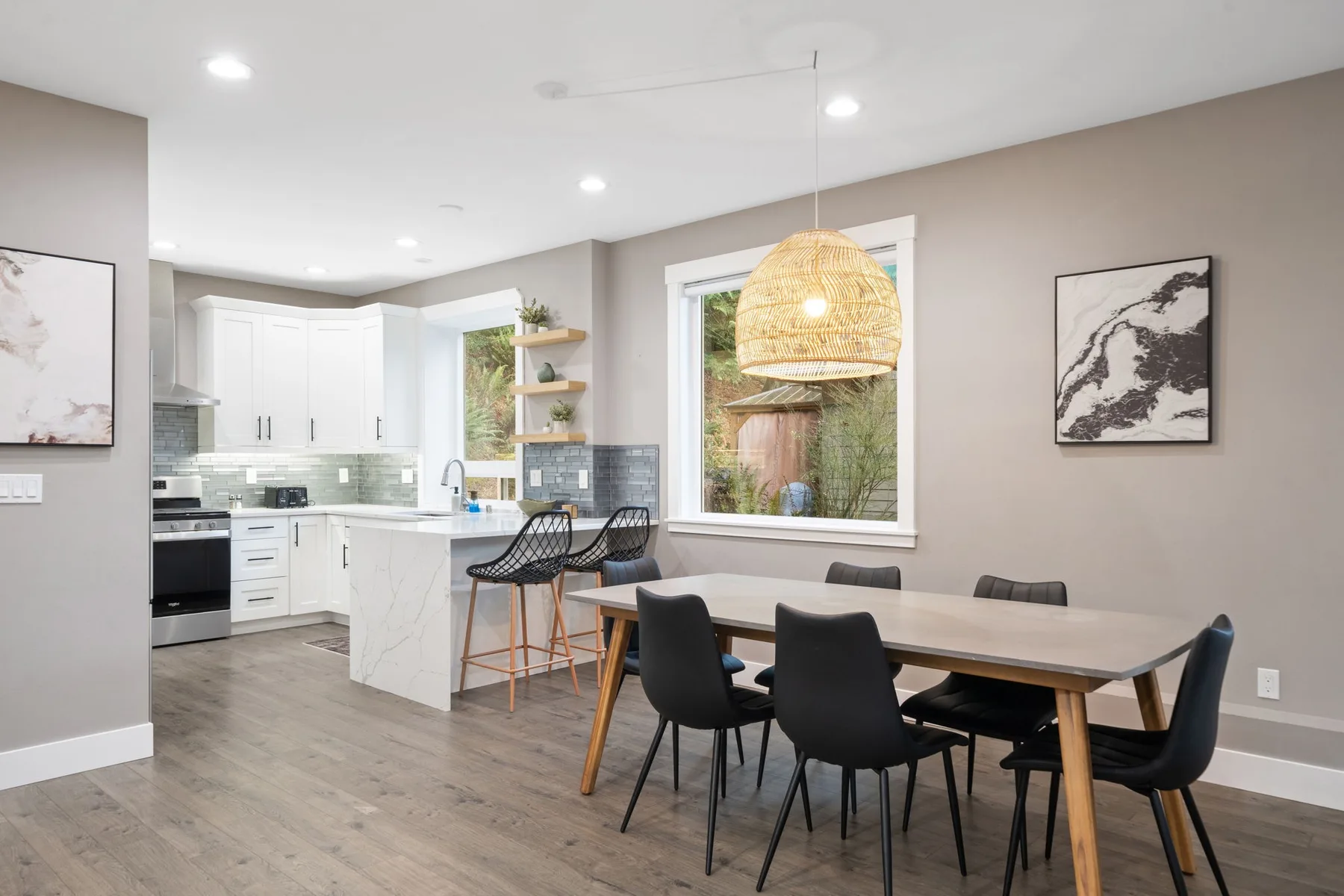 Cocina y comedor de concepto abierto, con una mesa bajo una lámpara colgante de fibras tejidas.