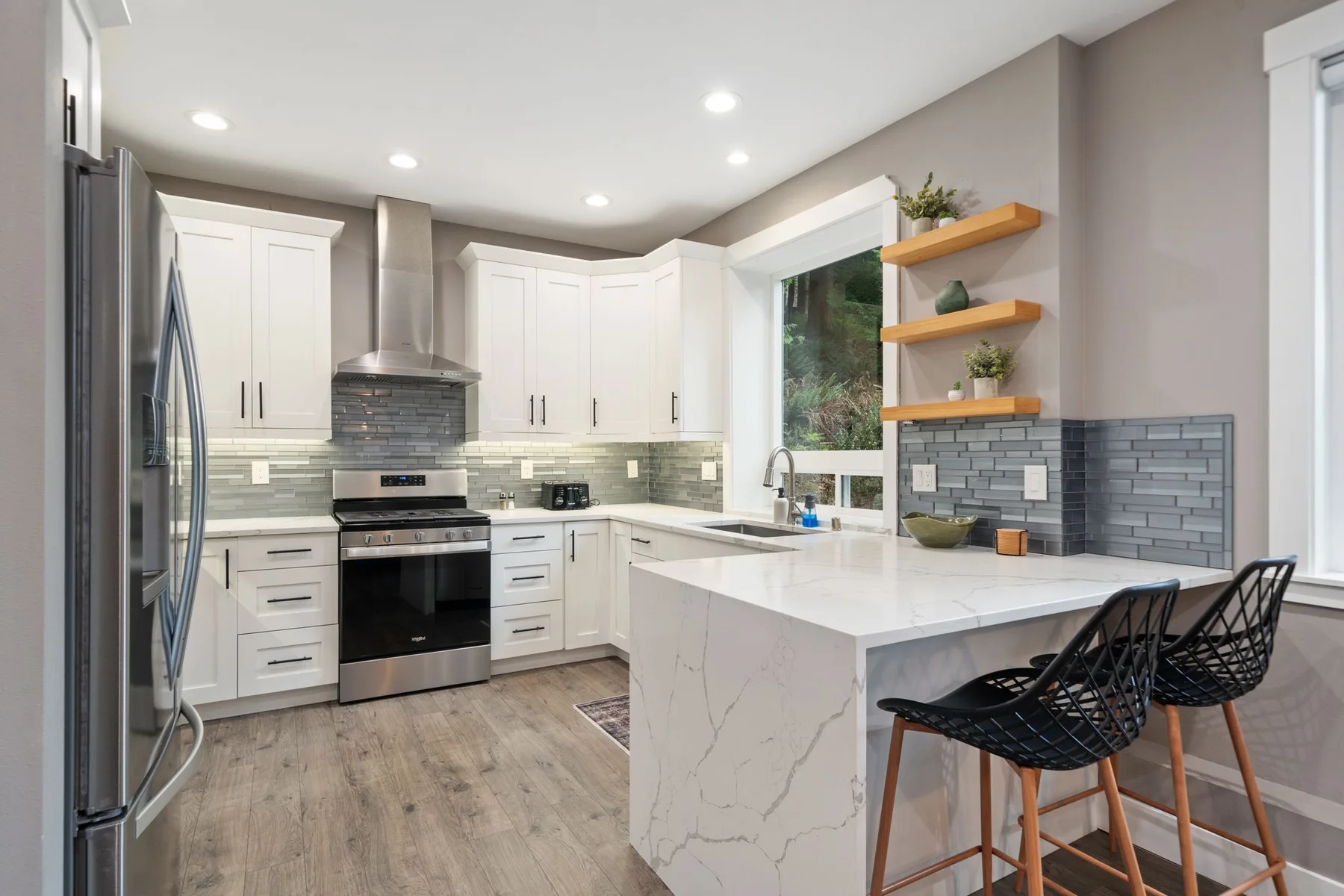 Una cocina moderna y luminosa con gabinetes blancos y una isla central con asientos.