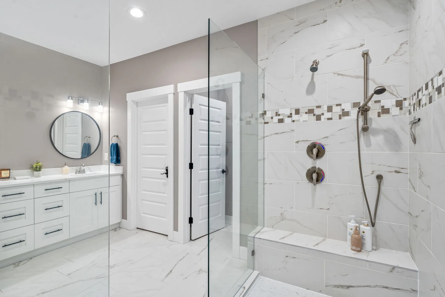 Un baño luminoso con un tocador blanco y una ducha con paneles de vidrio.