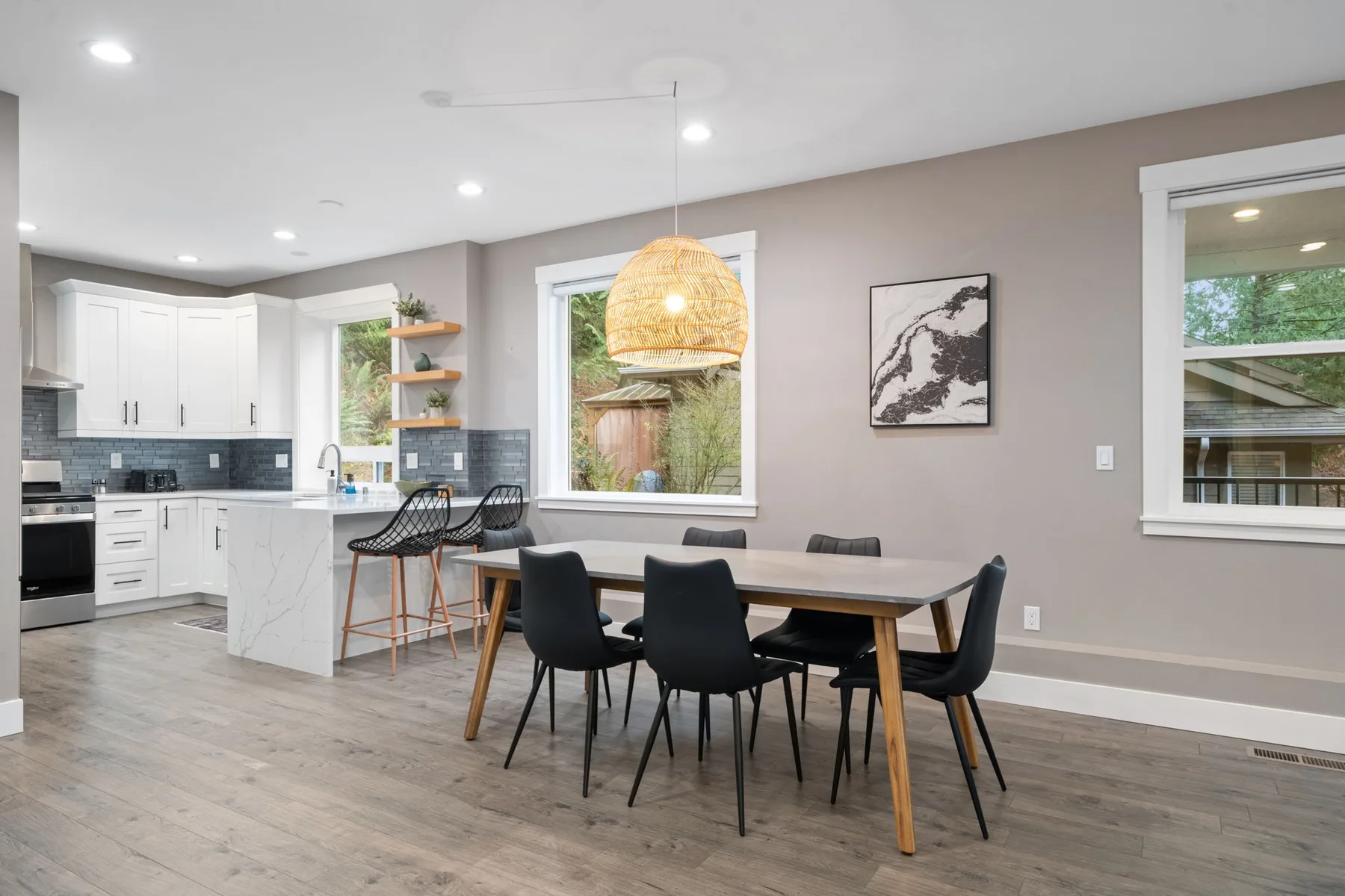 Cocina y comedor de planta abierta con una mesa bajo una lámpara colgante tejida.